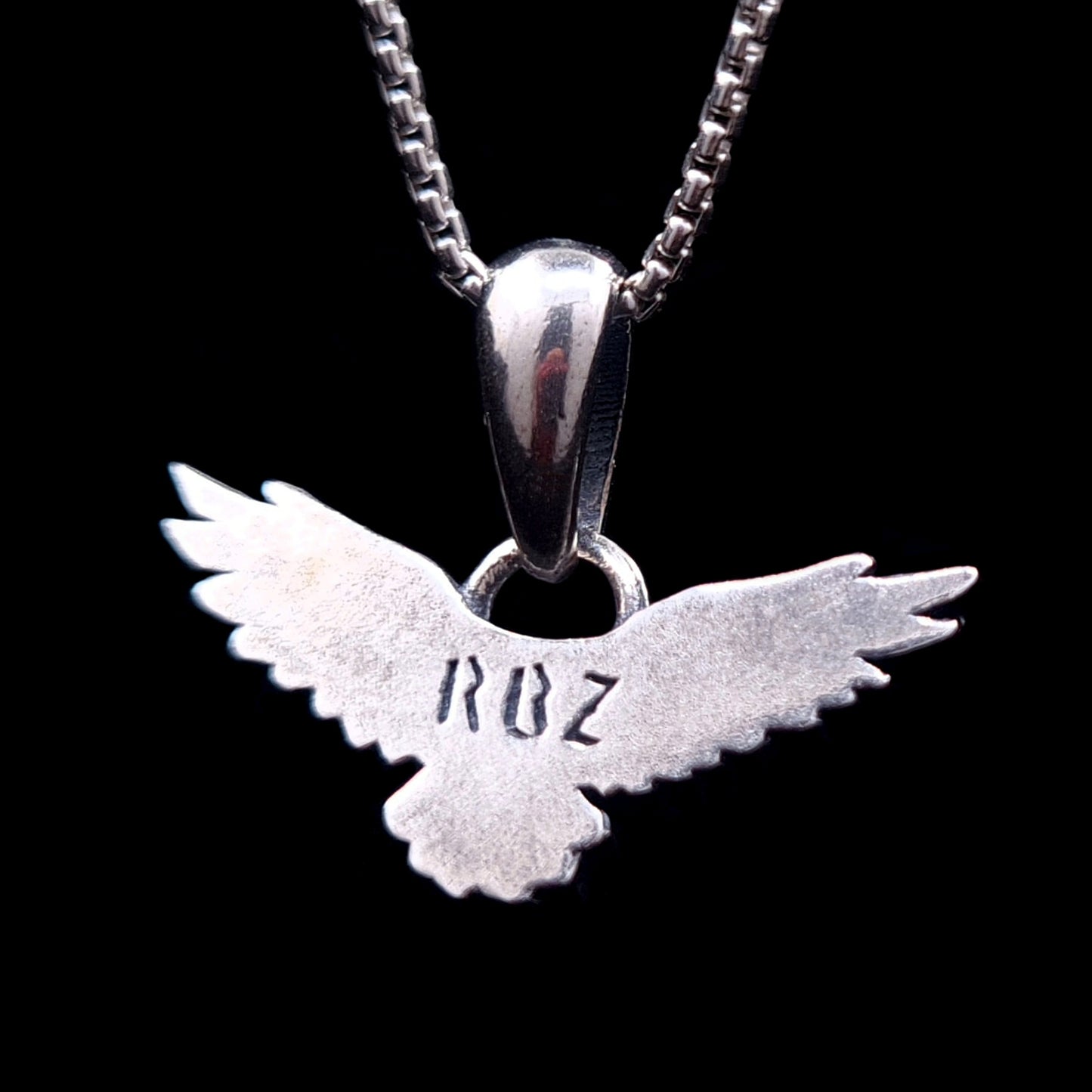 Back view of the sterling silver flying raven pendant featuring the RBZ brand engraving on the smooth reverse side, handcrafted Gothic crow necklace by RBZ Jewelry.
