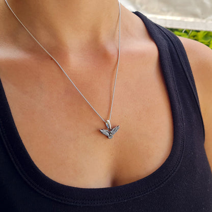 Sterling silver flying raven pendant worn by a female model on a sterling silver chain, showing the scale and fit of the handcrafted Gothic crow necklace by RBZ Jewelry.