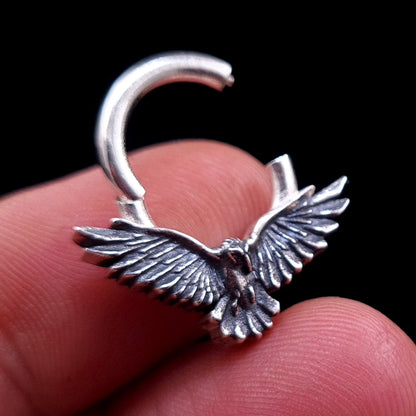 Sterling silver Dark Raven septum ring by RBZ Jewelry held between fingers, showing the clicker hinge in the open position to demonstrate the jewelry's opening mechanism.