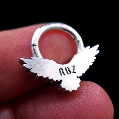 Back view of the Sterling silver Dark Raven septum ring by RBZ Jewelry held between fingers, showcasing the RBZ logo engraving on the smooth reverse side of the raven.