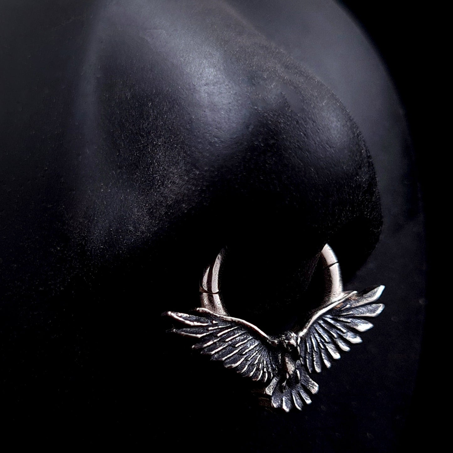 Sterling silver Dark Raven septum ring by RBZ Jewelry shown worn on a life-size black silicone nose model, illustrating the scale and appearance of the Gothic bird design in a realistic piercing placement.