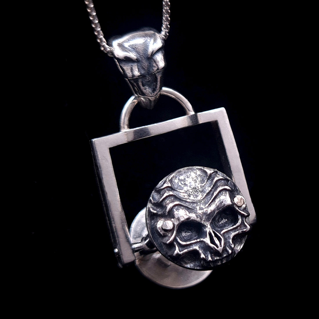 Frontal detail of the biomechanical skull cap on the kinetic Rotating Hourglass Pendant. Handcrafted in solid 925 sterling silver with an oxidized finish by RBZ Jewelry.