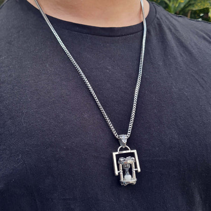 Male model wearing the Rotating Skull Hourglass Pendant on a long sterling silver chain. Shows the pendant's proportions and gothic aesthetic against a black t-shirt.