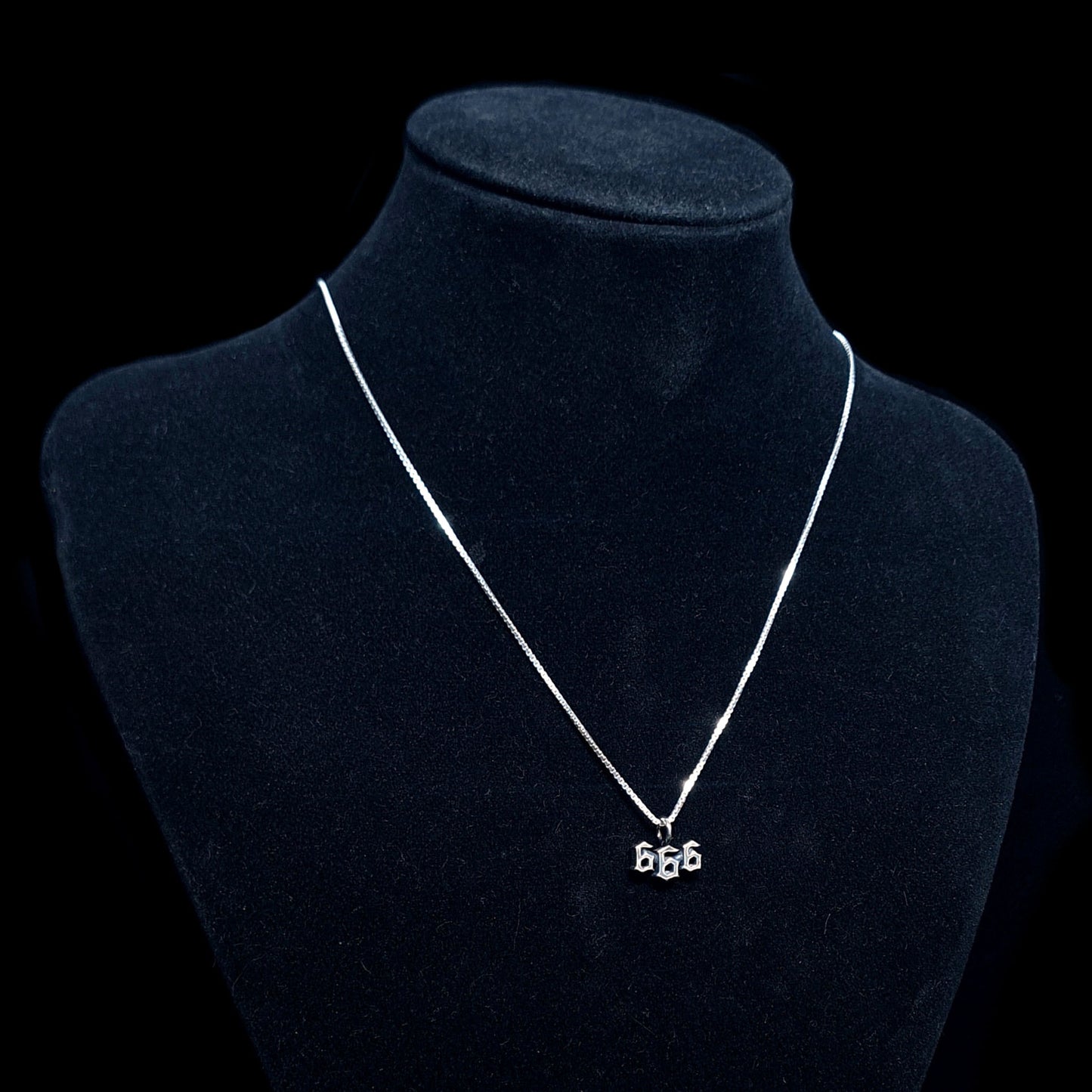 Dainty Sterling silver Gothic/Satanic 666 Number of the Beast pendant by RBZ Jewelry with an oxidized finish, shown on a silver chain on a black jewelry mannequin to demonstrate scale and how it sits when worn.