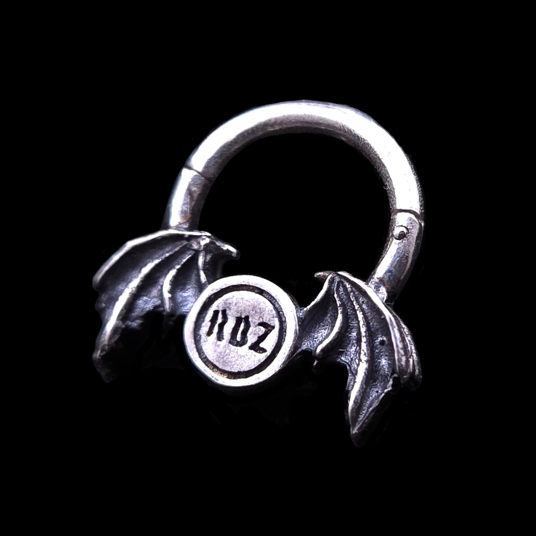 Rear view of the gothic 925 sterling silver winged septum clicker ring by RBZ Jewelry, showcasing the engraved RBZ brand logo on the back of the center pendant flanked by oxidized demon bat wings.