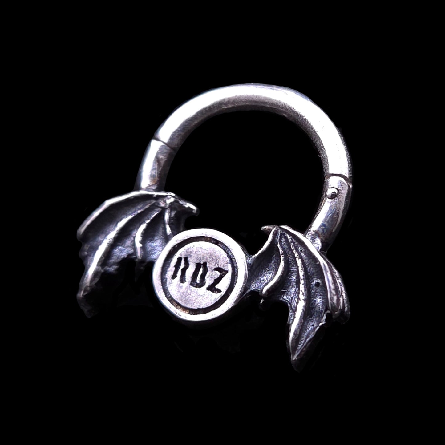 Rear view of the gothic 925 sterling silver winged septum clicker ring by RBZ Jewelry, showcasing the engraved RBZ brand logo on the back of the center pendant flanked by oxidized demon bat wings.