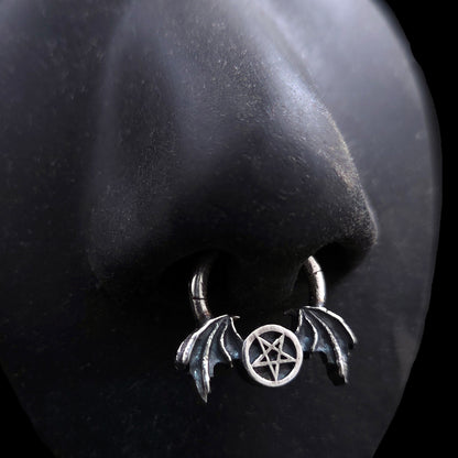 Gothic 925 sterling silver winged pentagram septum clicker ring by RBZ Jewelry modeled on a life-sized black silicone nose display to demonstrate fit and appearance when worn.