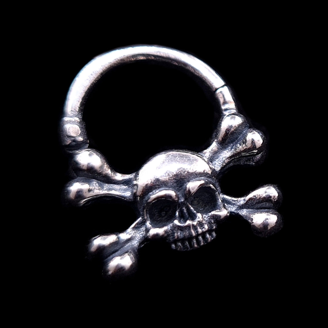 Hand-crafted Gothic sterling silver skull and crossbones septum clicker by RBZ Jewelry, featuring a weathered, oxidized finish and detailed memento mori design against a solid black background.