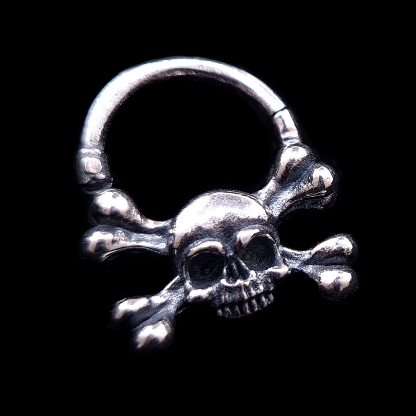 Hand-crafted Gothic sterling silver skull and crossbones septum clicker by RBZ Jewelry, featuring a weathered, oxidized finish and detailed memento mori design against a solid black background.