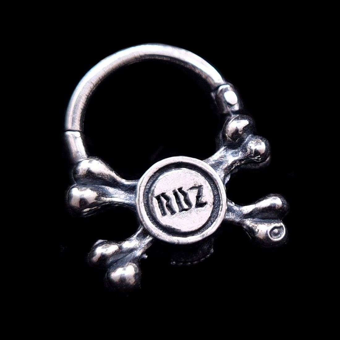 Back view of the sterling silver crossbones septum ring by RBZ Jewelry, showcasing the official RBZ maker's mark engraved in a gothic font on the reverse of the oxidized skull.
