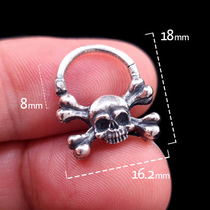 Detailed front view of the sterling silver crossbones skull septum ring by RBZ Jewelry, held in hand with dimension overlays indicating an 8mm inner drop, 18mm height, and 16.2mm width.