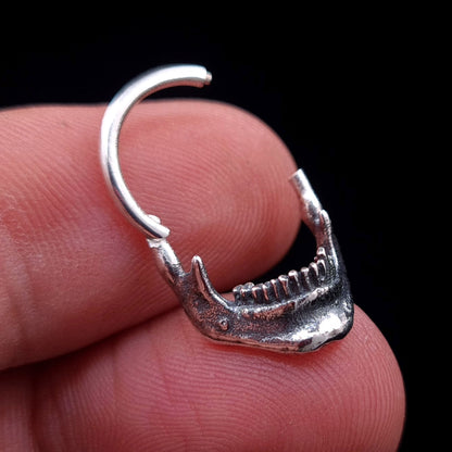 Sterling silver Reaped Mandible septum ring by RBZ Jewelry held in hand to show scale, featuring the gothic anatomical jaw design and the clicker mechanism in the open position.