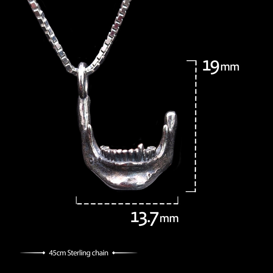 Frontal view of the RBZ Jewelry oxidized sterling silver Skull Jaw pendant with dimension overlays showing a height of 19mm and width of 13.7mm. The detailed gothic mandible charm is suspended from a 45cm sterling silver box chain against a black background.