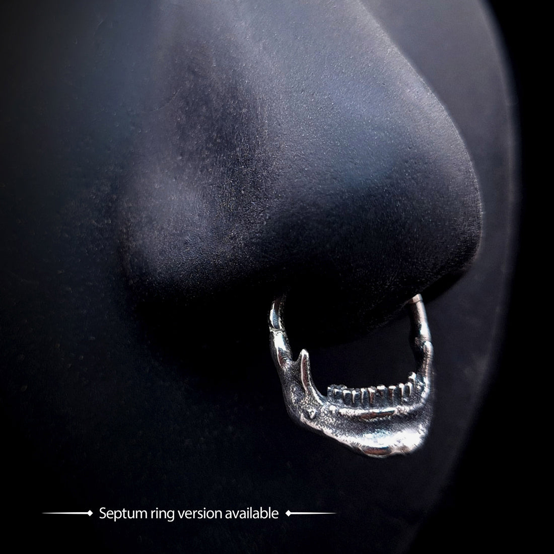 Handcrafted sterling silver skull jaw septum clicker by RBZ Jewelry, shown worn on a black mannequin nose to demonstrate the fit. The detailed gothic mandible design with oxidized skeletal texture is featured as an alternative body jewelry option, with text indicating this version is available.