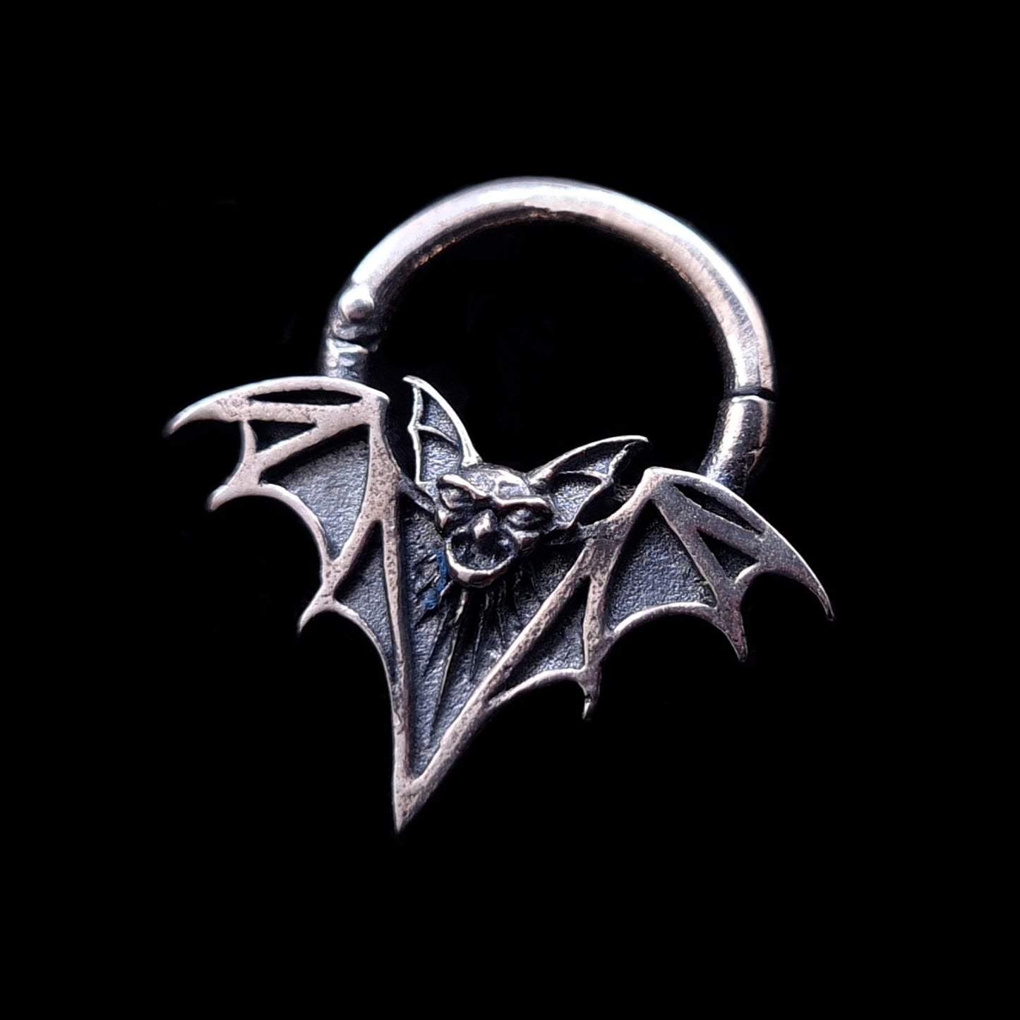Sterling silver Gothic vampire bat septum clicker ring by RBZ Jewelry, featuring a detailed bat face and skeletal wings with a deep oxidized finish against a black background.
