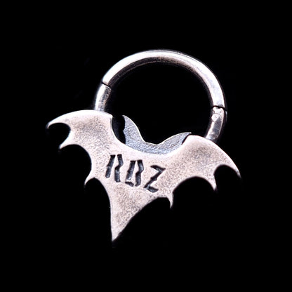 Back view of the sterling silver Gothic vampire bat septum clicker ring by RBZ Jewelry, showcasing the RBZ logo engraved on the smooth oxidized silver surface against a black background.