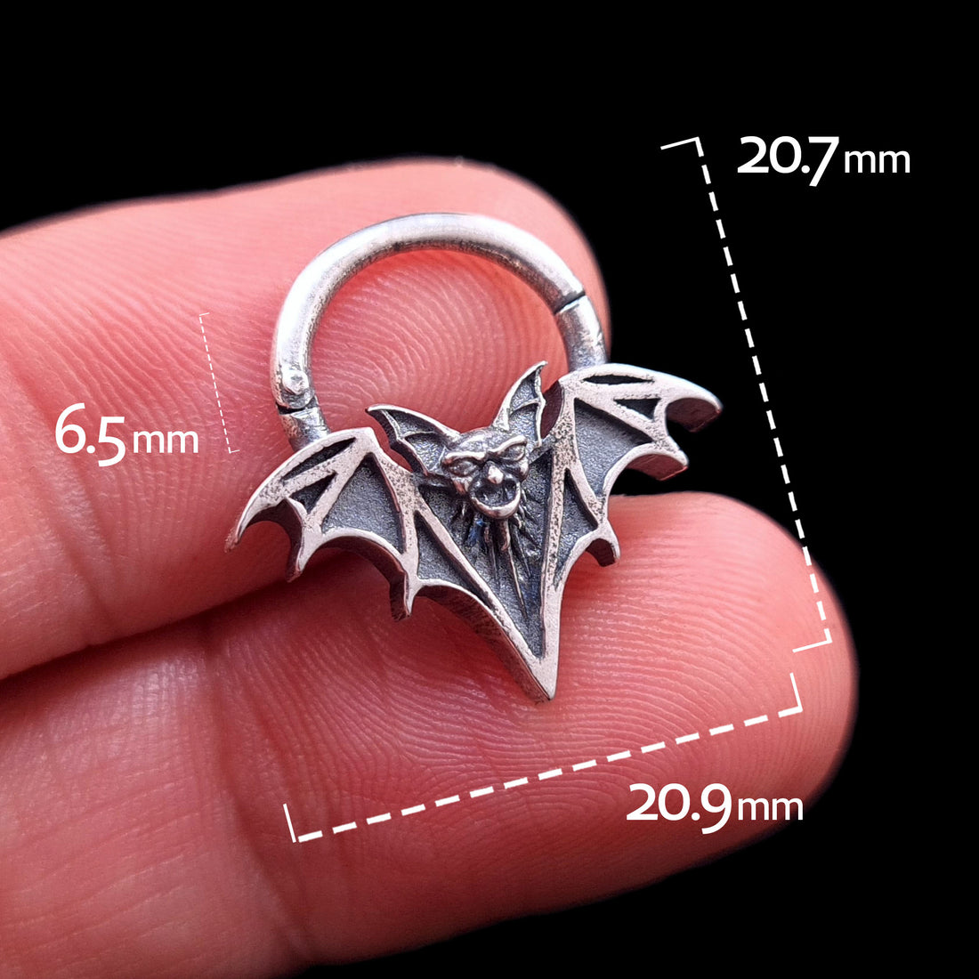 Front view of the sterling silver Gothic vampire bat septum clicker by RBZ Jewelry held in hand, featuring dimension overlays: Approx 20.7mm total height, 20.9mm width, and 6.5mm internal diameter.