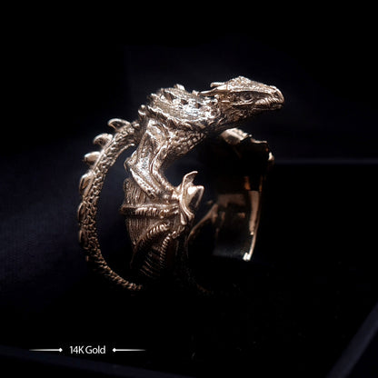 Gothic solid 14K gold dragon ring by RBZ Jewelry, showcasing highly detailed scales, sculpted webbed wings, and an intricate interlocking wrapped tail design with contrasting dark shadows against a black background.
