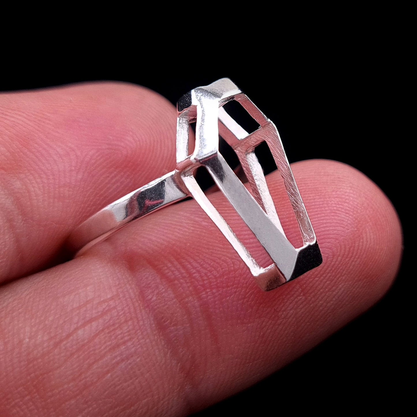 Sterling silver Minimalist Coffin ring by RBZ Jewelry, held between two fingers to demonstrate scale, showing the hollow geometric frame and architectural Gothic design.