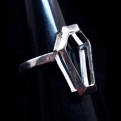 RBZ Jewelry Sterling Silver Minimalist Coffin Ring with hollow architectural frame and intricate geometric design facing right on a dark mandrel. The skeletal coffin-shaped setting is open to create light and shadow effects.