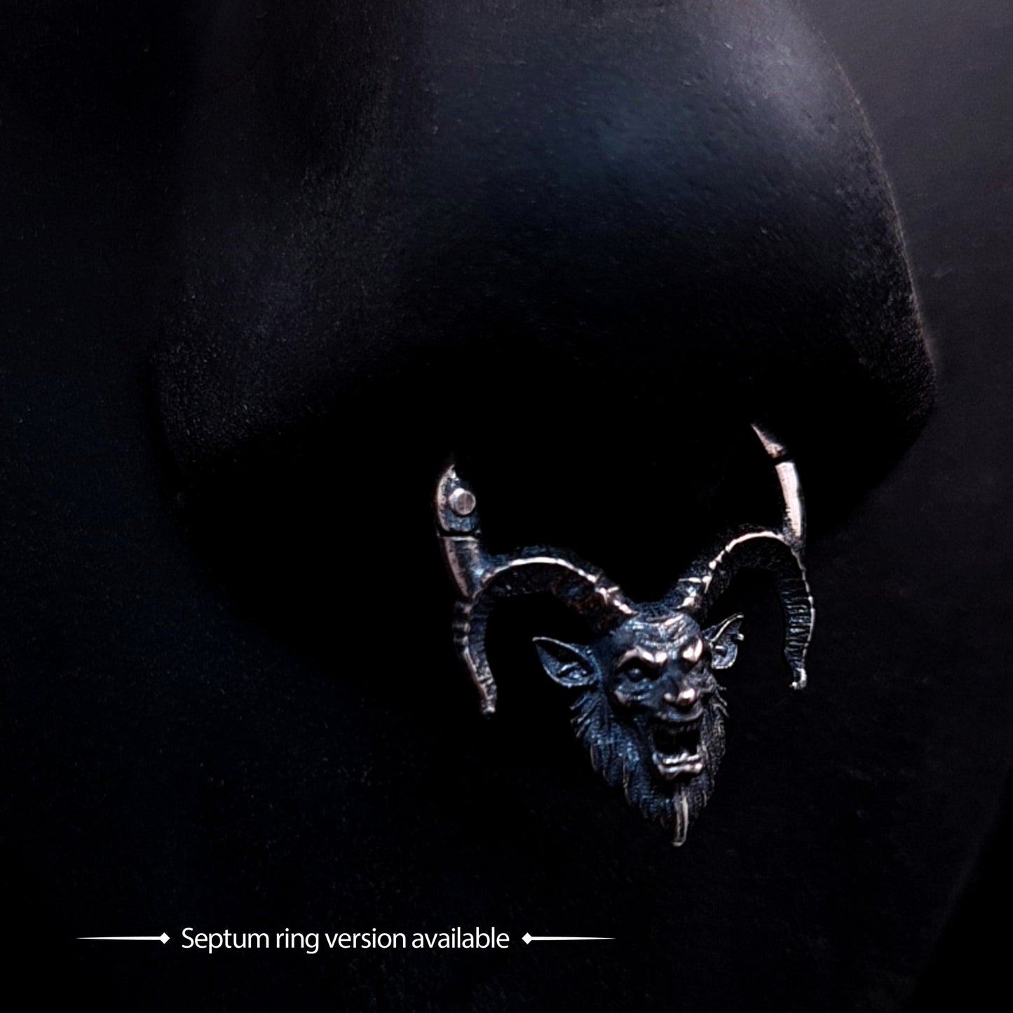 RBZ Jewelry Gothic Sterling Horned Demon septum clicker ring: An intricate, oxidized sterling silver demon head with snarling facial details and sweeping ridged horns, integrated into a hinged septum ring and displayed on a black nose mannequin against a dark background. Text at the bottom reads "Septum ring version available."