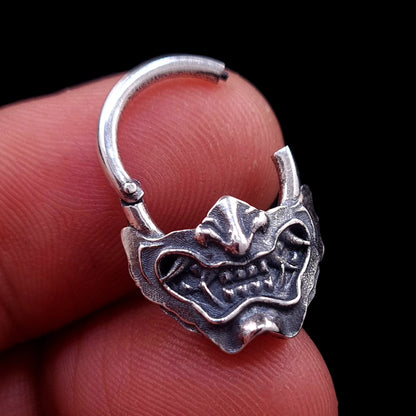 Sterling silver Samurai Oni mask septum ring by RBZ Jewelry, shown open and held in hand to demonstrate the clicker mechanism and scale.