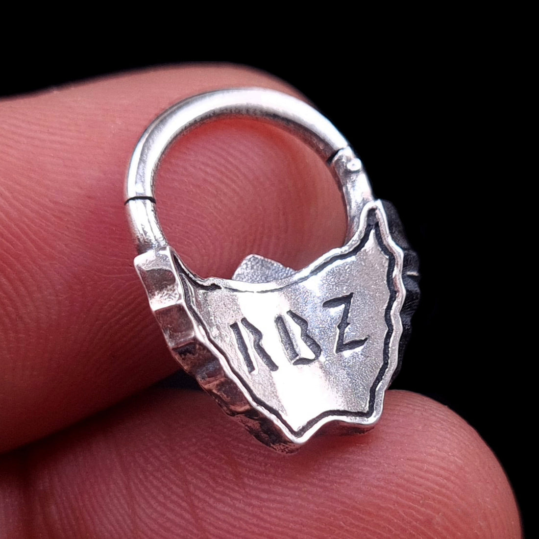 Sterling silver Samurai Oni mask septum ring by RBZ Jewelry, held in hand to show the back view with the RBZ logo engraving and clicker mechanism.