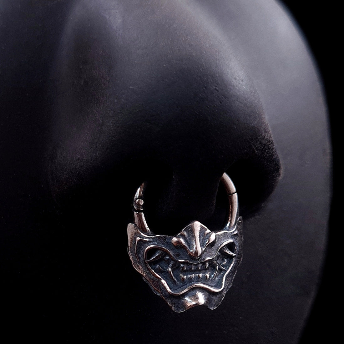 Sterling silver Samurai Oni mask septum ring by RBZ Jewelry, shown worn on a life-size black silicone nose model to demonstrate fit and appearance.