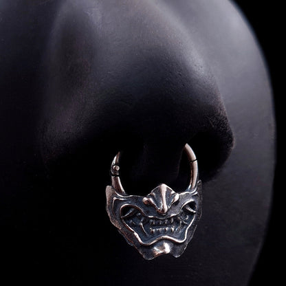 Sterling silver Samurai Oni mask septum ring by RBZ Jewelry, shown worn on a life-size black silicone nose model to demonstrate fit and appearance.