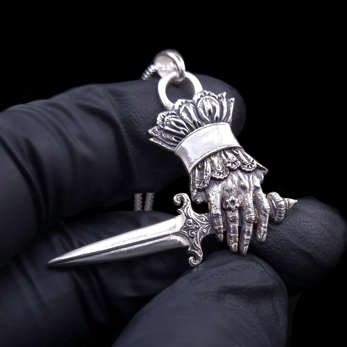 RBZ Jewelry Judith and Holofernes pendant held in a black-gloved hand, showing the sculpted hand, dagger scrollwork and Star of David ring
