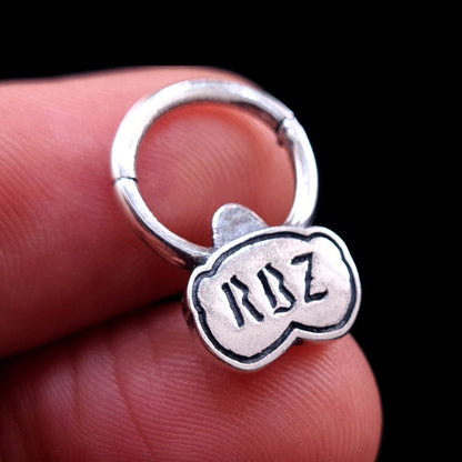 Close-up of the back of the sterling silver Jungle Gorilla septum clicker ring by RBZ Jewelry held between fingers, showcasing the engraved RBZ logo and providing a sense of scale for the detailed jewelry piece.