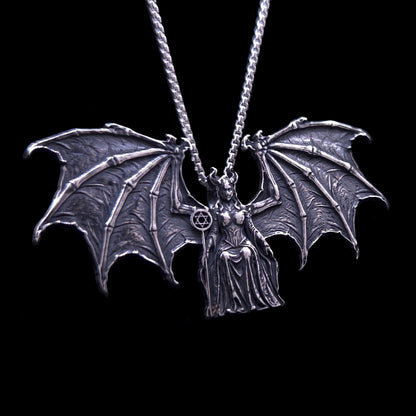 A highly detailed RBZ Jewelry Gothic Sterling silver pendant of the figure Lilith, who is enthroned between expansive, intricate, skeletal bat wings. The pendant features high-contrast dark oxidation, detailed armor on the figure, and a small scepter held in her right hand topped with a horned Star of David. Hanging from a silver chain against a solid black background.