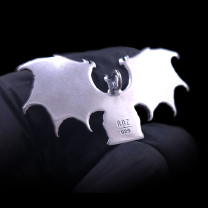 Scale shot of the reverse side of the RBZ Jewelry Gothic Sterling silver Lilith Demon Angel pendant held in a black-gloved hand, displaying its polished back stamped with the RBZ hallmark and 925 purity mark.