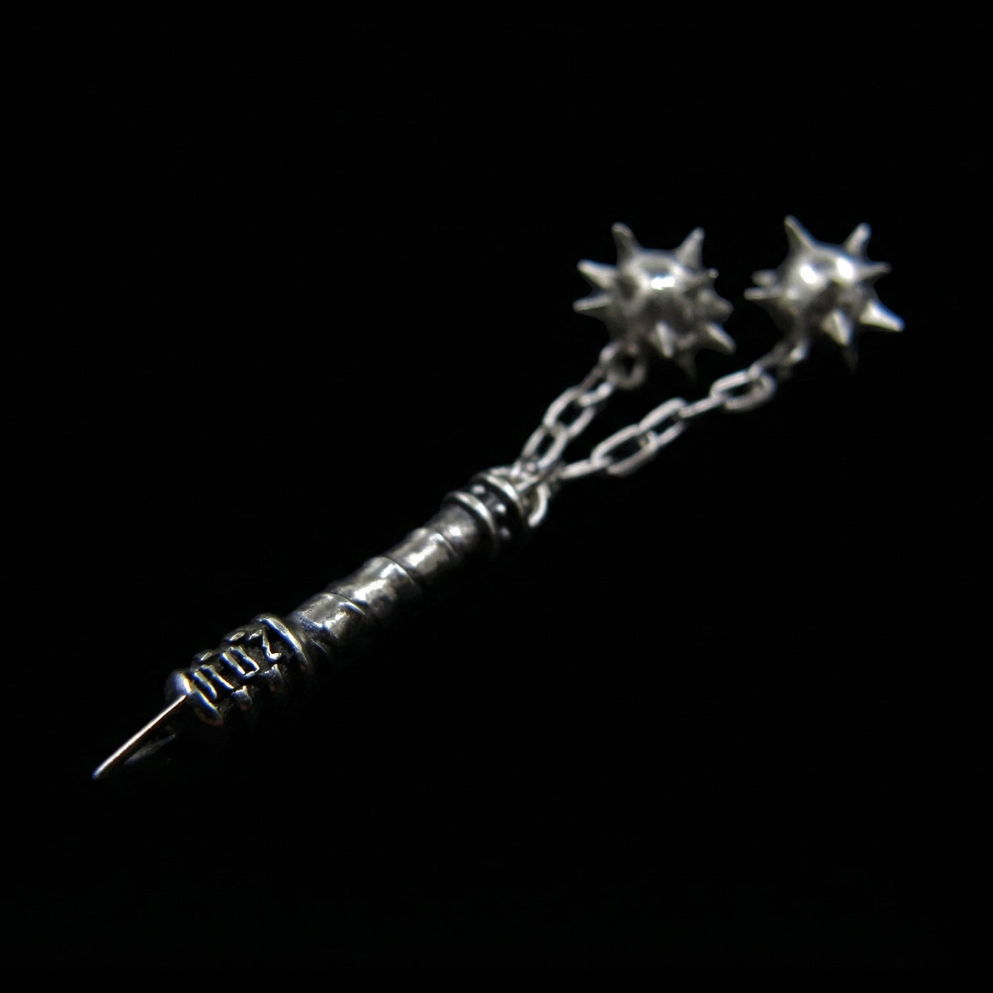 Side view of the Sterling silver Flail Crusher pendant by RBZ Jewelry, highlighting the engraved RBZ logo on the handle base and two sharp spiked spheres on chains in a gothic medieval style.