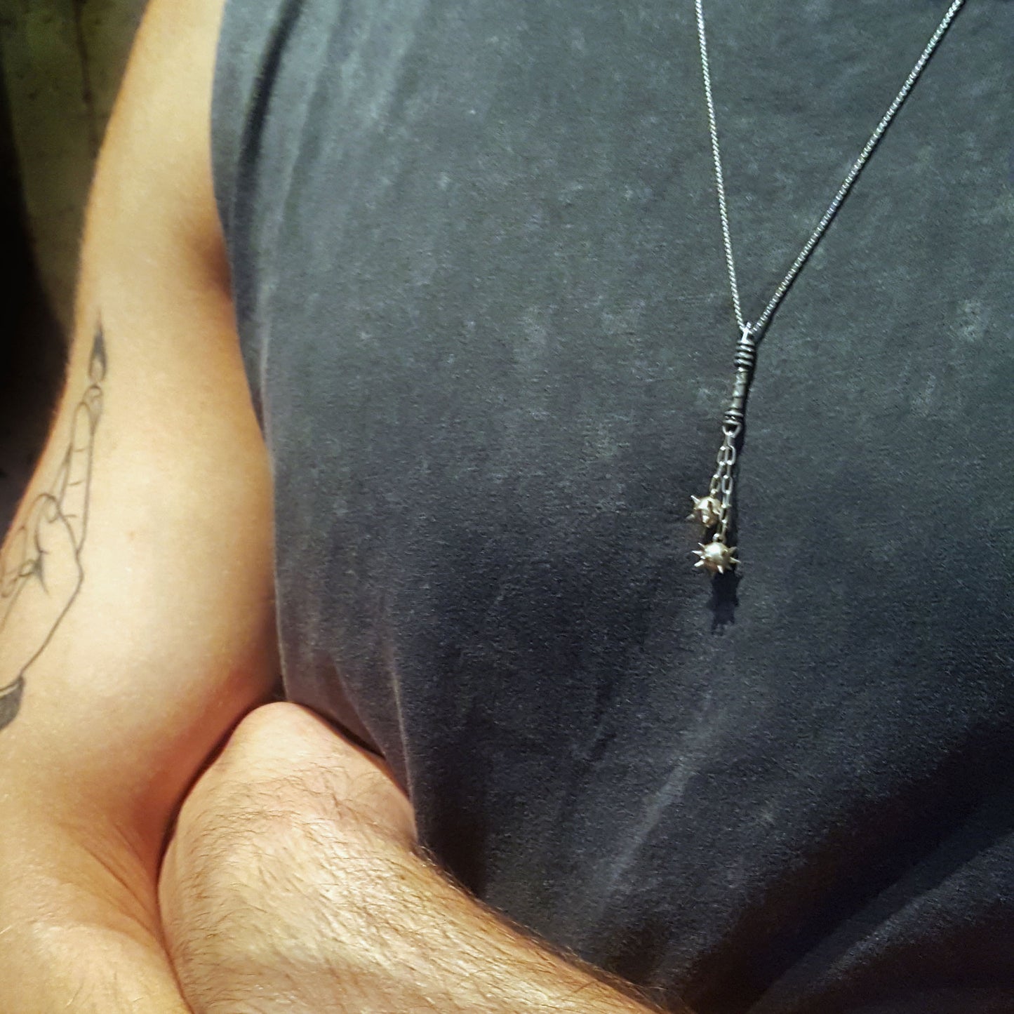 Sterling silver Flail Crusher pendant by RBZ Jewelry worn by a male model over a dark grey sleeveless shirt, showcasing the scale and gothic aesthetic of the handcrafted spiked mace spheres and spiral-textured handle.
