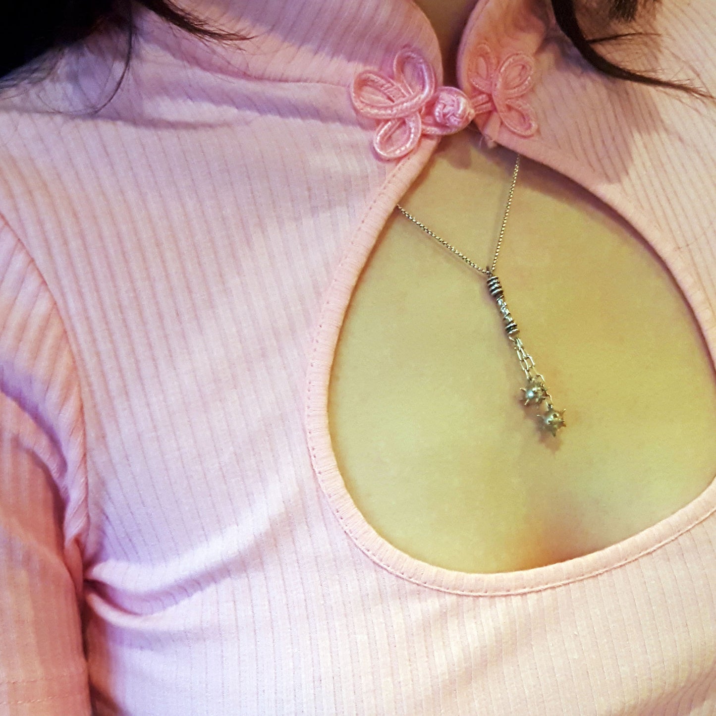 Sterling silver Flail Crusher pendant by RBZ Jewelry worn by a female model over a pink ribbed top with a keyhole neckline, showcasing the scale and gothic weapon design of the handcrafted spiked spheres and detailed handle.