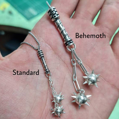 Size comparison of the Sterling silver Flail Crusher pendant by RBZ Jewelry, showing the Standard (45mm) and Behemoth (76mm) versions held in a hand to demonstrate scale, both featuring handcrafted spiked mace spheres and spiral-textured handles.