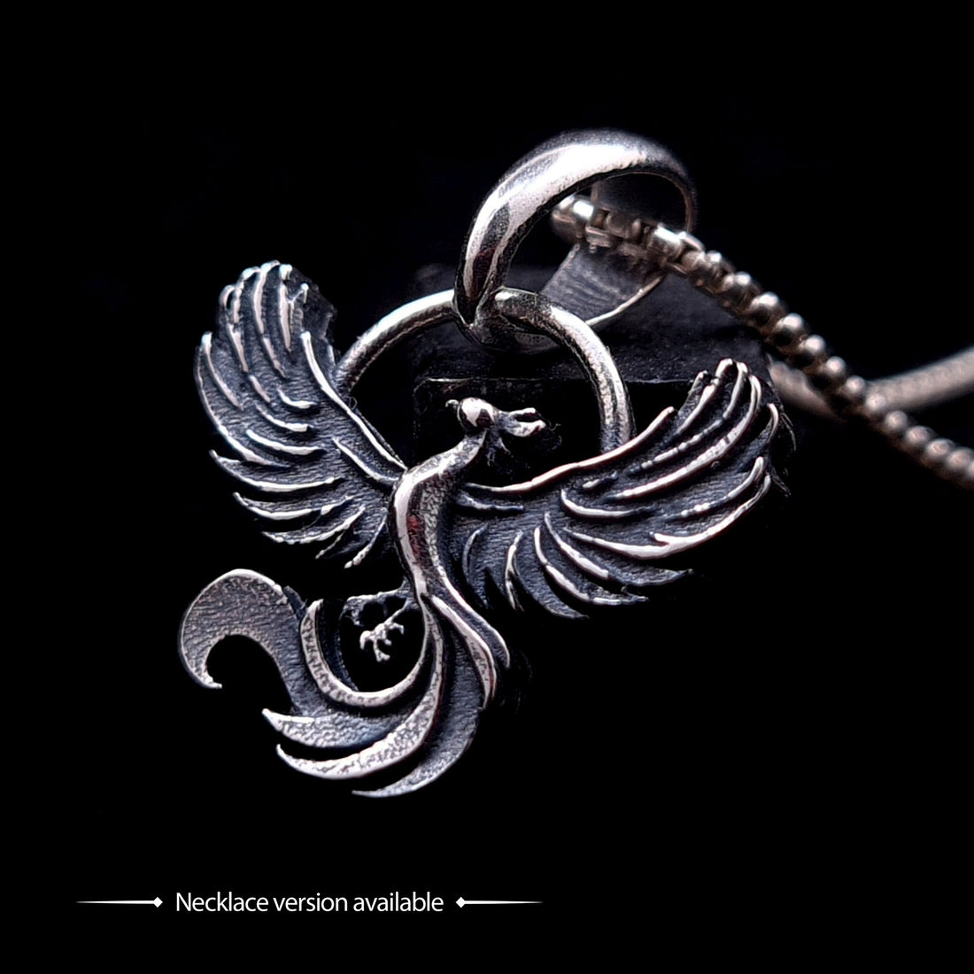 Sterling silver Soaring Phoenix pendant by RBZ Jewelry, showcasing the signature intricately carved phoenix design with outstretched wings suspended from a polished bail on a metal chain, isolated on a black background with a caption stating "Necklace version available."