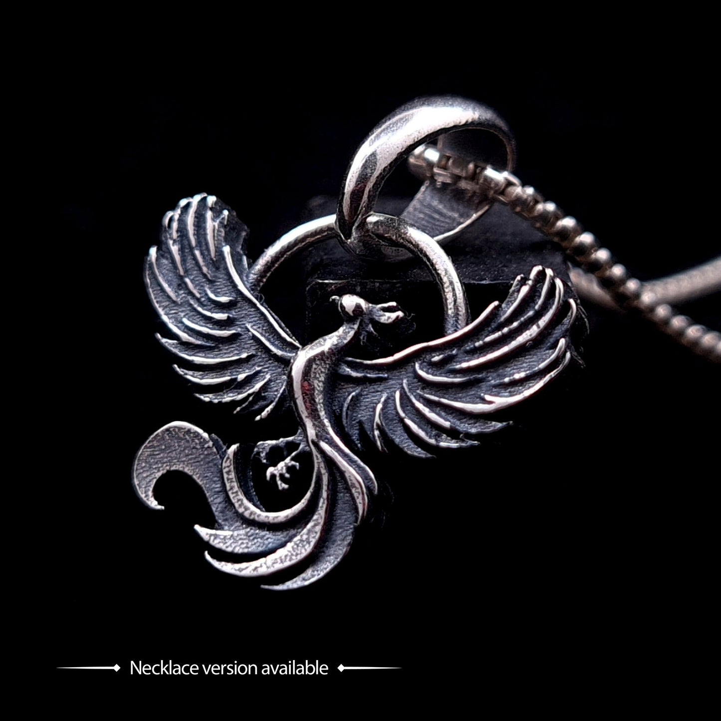 Sterling silver Soaring Phoenix pendant by RBZ Jewelry, showcasing the signature intricately carved phoenix design with outstretched wings suspended from a polished bail on a metal chain, isolated on a black background with a caption stating "Necklace version available."