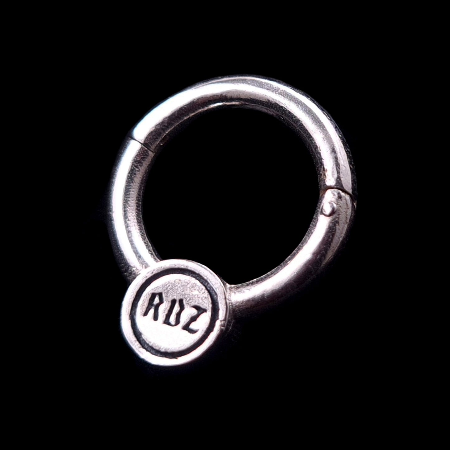 Back view of the RBZ Jewelry Sterling silver Star of David septum clicker ring. The reverse side of the circular medallion features the brand's hallmark, with the letters 'RBZ' stamped in a stylized, calligraphic font.