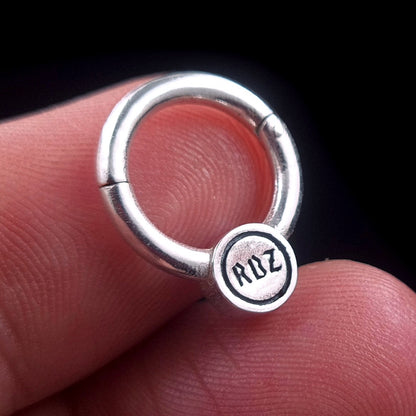 Back view of the Sterling silver Star of David septum clicker ring by RBZ Jewelry, held in hand to showcase the 'RBZ' hallmark stamped on the reverse side of the medallion.