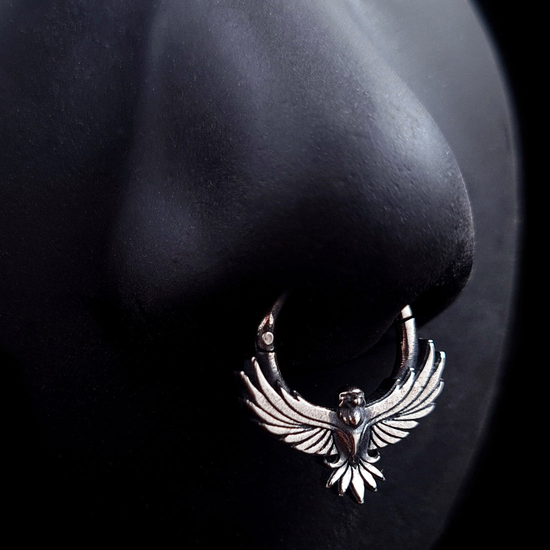 Sterling silver Tribal Eagle septum ring by RBZ Jewelry worn on a black silicone nose model, demonstrating the fit and scale of the gothic eagle design with its outstretched wings.