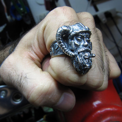 Sterling silver Viking warrior ring by RBZ Jewelry worn on a male clenched fist, showcasing the bold, heavy-duty design and intricate warrior head detail in a workshop environment.