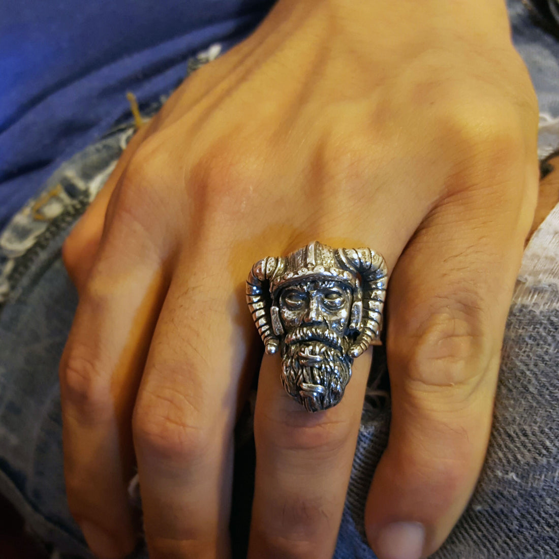 Sterling silver Viking warrior ring by RBZ Jewelry shown on a male hand, highlighting the large, hand-sculpted warrior face and horned helmet in a lifestyle shot against a denim background.