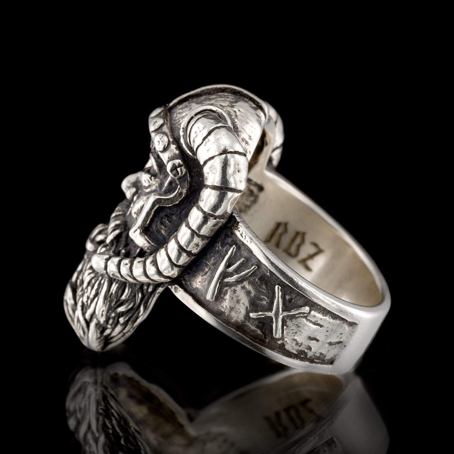 Sterling silver Viking warrior ring by RBZ Jewelry, shank view showing the detailed runic inscriptions on the band and the internal RBZ hallmark, set against a black reflective background.