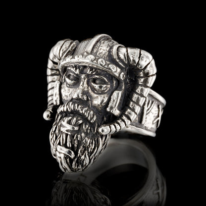 Sterling silver Viking warrior ring by RBZ Jewelry, featuring an intricately hand-sculpted warrior face with a detailed beard and a curved horned helmet, presented in a front view on a black reflective background.